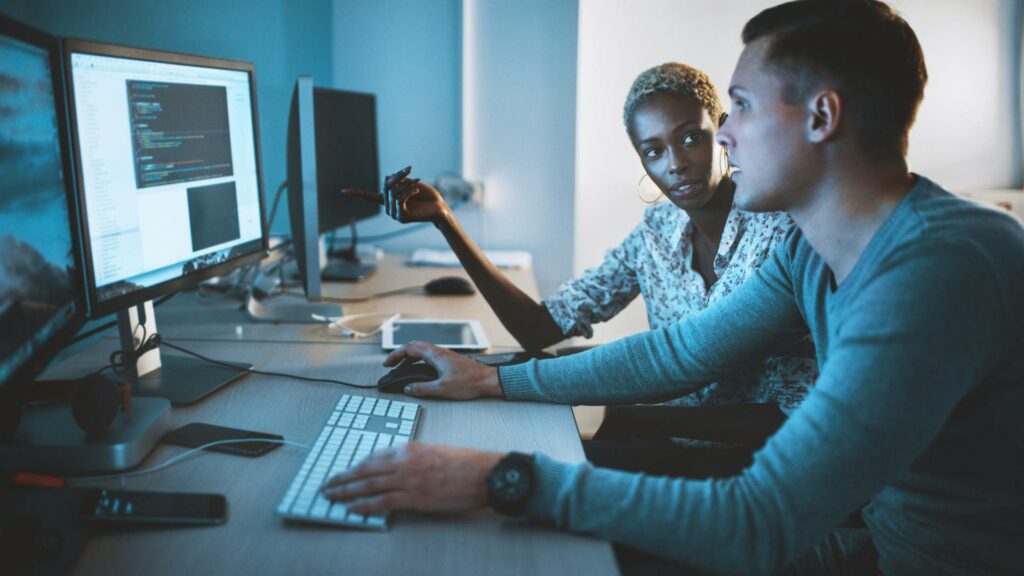 Two web developers work on a desktop computer on web design and web development.