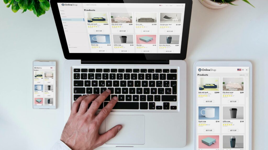 A laptop, tablet, and phone are displayed on a white desk with the same web design on each device.