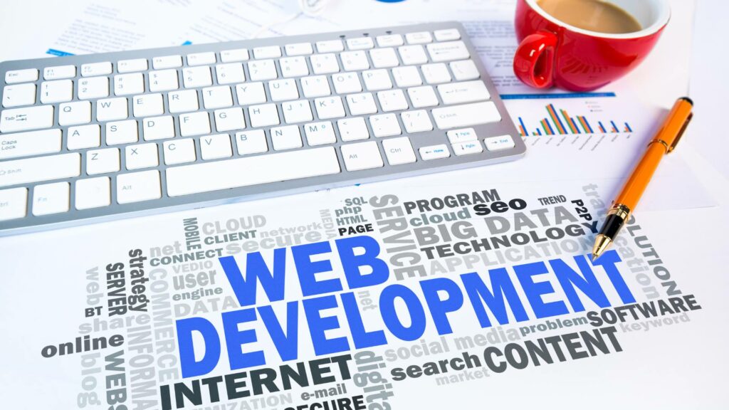 A graphic that says Web Development in big blue letters is displayed under a keyboard, red mug of coffee, and orange pen.