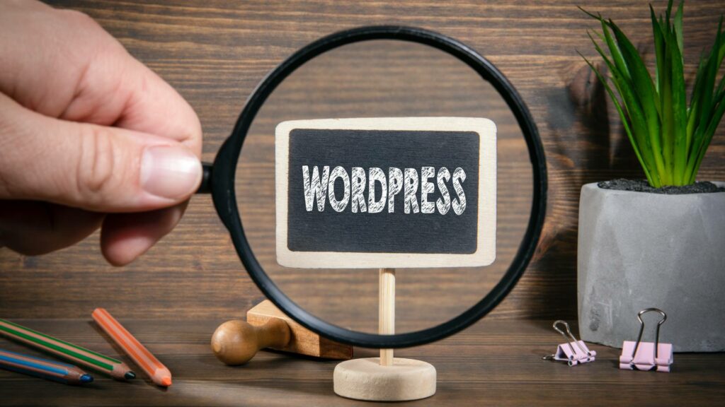 The word WordPress is displayed on a mini chalk board, and a hand holds up a magnifying glass to the chalkboard.