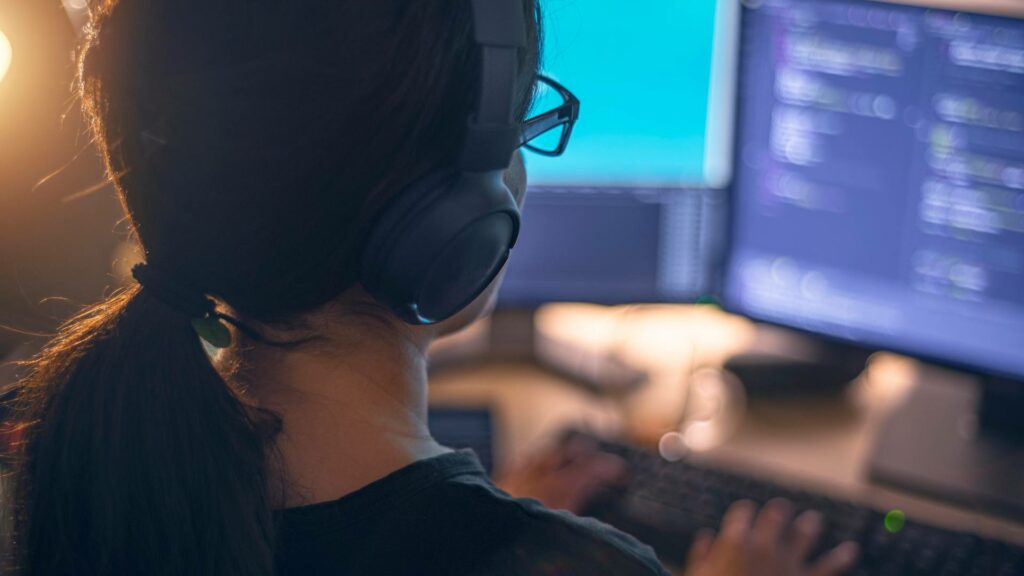 A woman works on a desktop computer with two monitors, demonstrating creative front end development tactics.