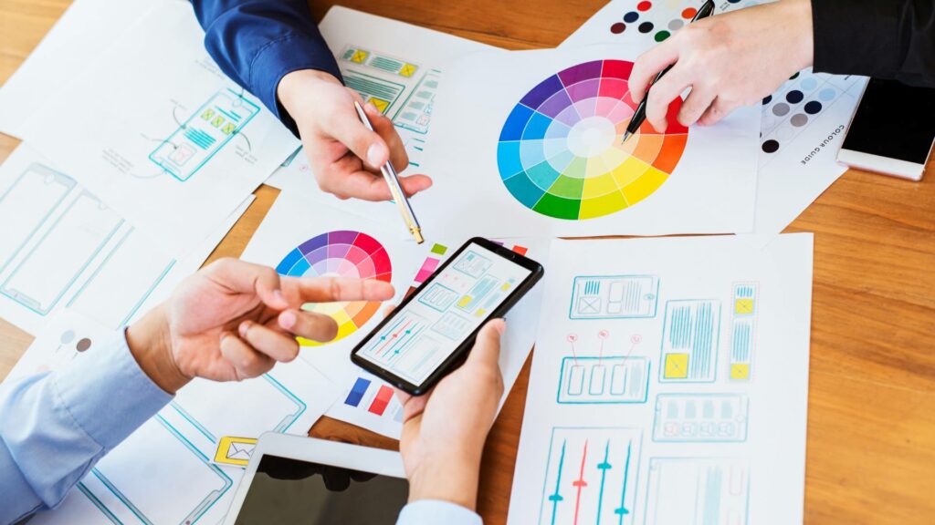 Colorful designs are spread out on a wooden table, demonstrating options for UI design.