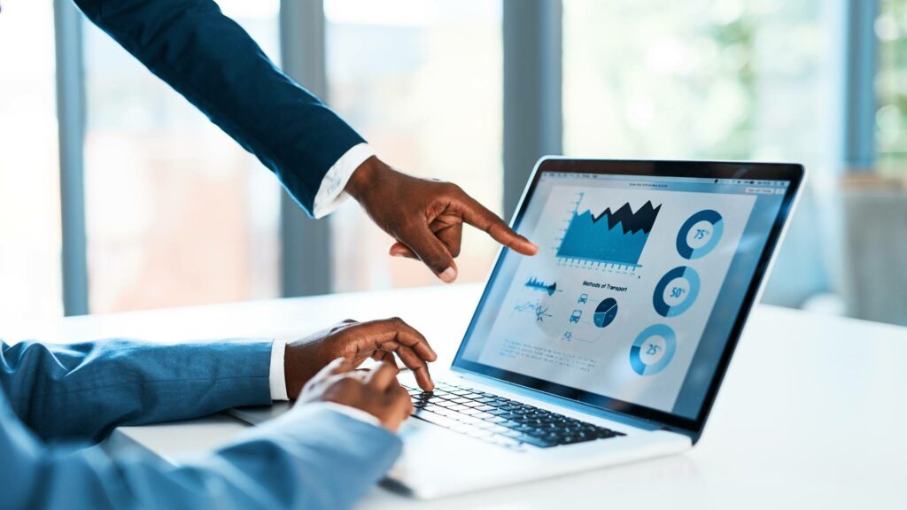 A laptop screen is displayed with charts and graphs, demonstrating software tools.