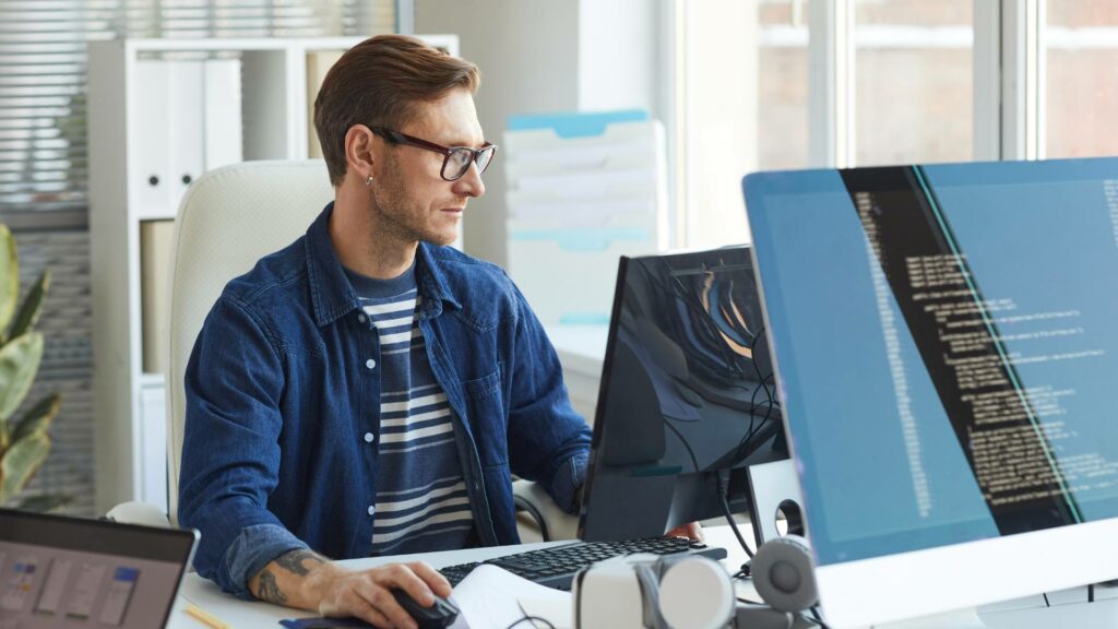 A web app developer works on a desktop computer, demonstrating Graphem Solutions and their capable team.