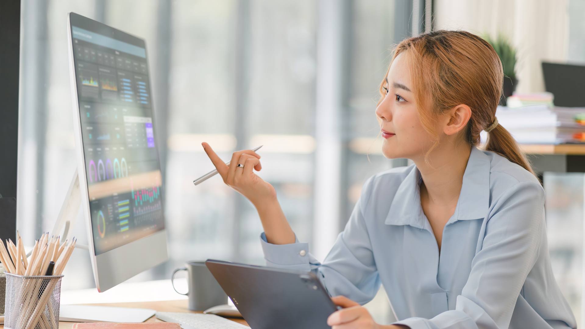 A woman sits at her desk and works on a crm system.