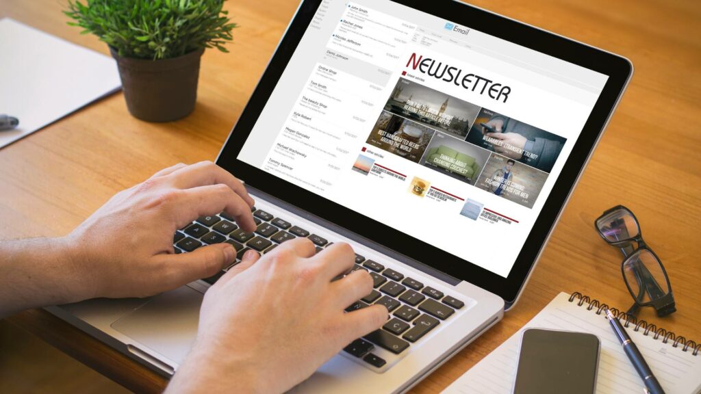 A newsletter is displayed on a laptop as someone types on the keyboard.